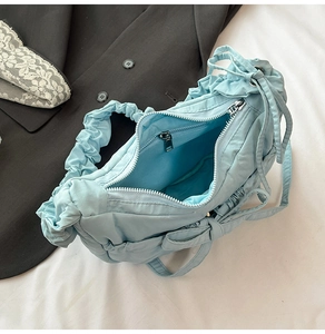 Detailed interior of light blue nylon pleated bag showing inner pocket and zipper