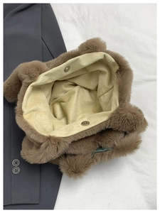 Macro view of plush brown tote bag featuring metal magnetic buckles and soft beige lining