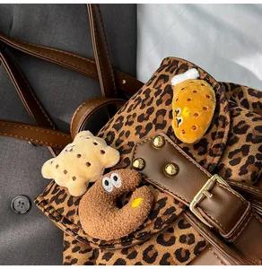 Detailed shot of leopard print backpack featuring cute cartoon plush charms and leather trim