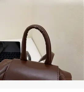 Detail of ergonomic dark brown leather handle on a quilted fashion backpack
