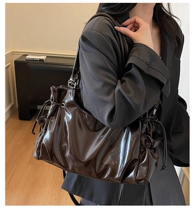 Detail of dark brown glossy shoulder bag showing drawstring pleats and oil wax texture