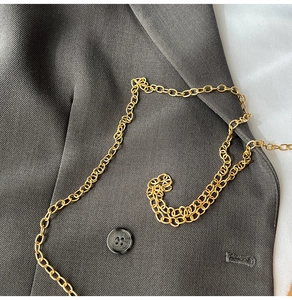 Close-up of golden alloy metal chain strap with polished oval rings on a fabric texture