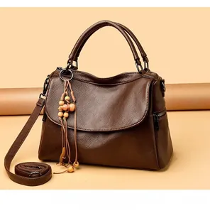 Detail of dark brown pebble leather handbag with wooden bead charm and metal zipper