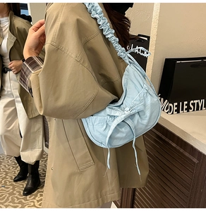 Detail of light blue pleated nylon shoulder bag featuring a cute bow and ruched strap