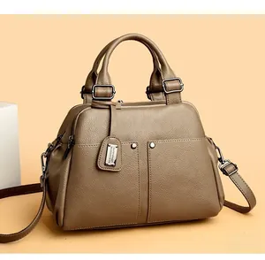 Close-up of khaki pebbled leather Boston bag with rivet pocket detail and metallic hardware