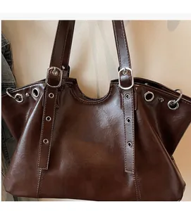 Detail of dark brown faux leather tote with shiny texture and silver metallic eyelets