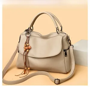 Detail of cream leather handbag with wooden bead tassel charm and adjustable shoulder strap