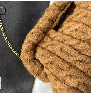 Close-up of brown chunky cable knit bag with gold chain strap and textured fabric detail
