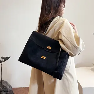 Détail du grand sac cabas noir mat avec fermoirs dorés porté par un mannequin