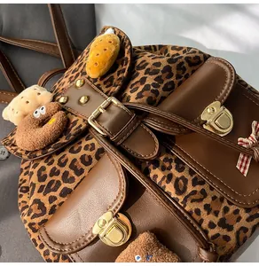Detail of leopard print plush backpack featuring golden buckle and cute charms
