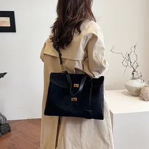 Détail du sac cabas en daim noir mat avec fermoir en métal doré et poignées en cuir chic