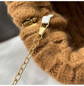 Close-up of golden chain strap and buckle detail on a brown knit shoulder bag