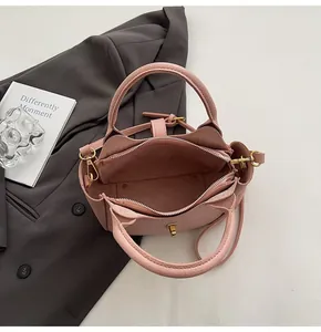 Detail of pink lychee leather bucket bag with top zipper and gold lock hardware
