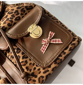 Close-up of leopard print and brown leather backpack with gold buckle and bow detail