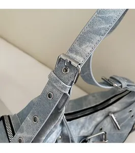 Gros plan des boucles métalliques argentées et des œillets sur le sac en jean délavé