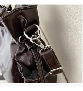 Close-up of glossy dark brown leather bag with shiny silver metal hardware and d-ring