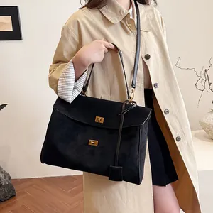 Gros plan du sac cabas en daim noir avec boucle dorée et bandoulière en cuir fin