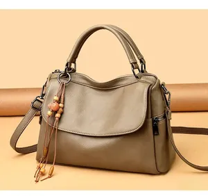 Close-up of light brown lychee textured leather bag with beaded tassel detail and metal zipper