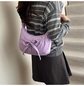 Detail of purple nylon shoulder bag with a large bow decoration and pleated texture