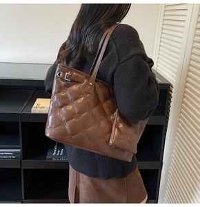 Détail d'un sac cabas en cuir matelassé marron foncé avec gaufrage floral et boucle métal