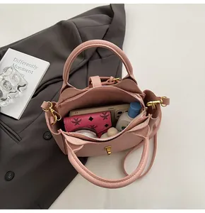 Close-up of pink litchi grain leather bucket bag with top handles and adjustable strap