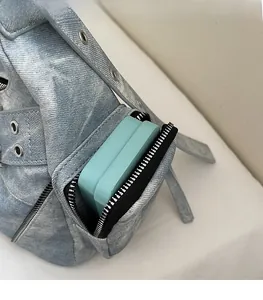 Gros plan d'une poche latérale zippée sur un sac bandoulière en denim avec petit étui