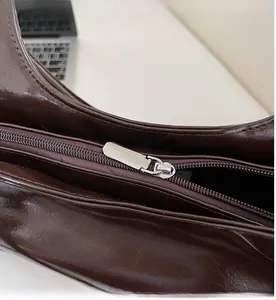 Close-up of smooth silver metal zipper on vintage dark brown glossy shoulder bag
