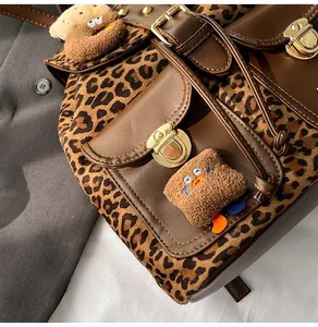 Detail of leopard print backpack with brown leather flap and plush toast charms