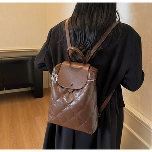Brown quilted leather backpack shown on a model with detailed floral embroidery pattern