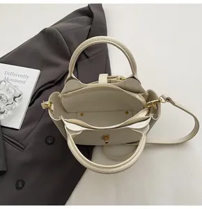 Close-up of beige lychee grain leather bucket bag with dual interior compartments and gold lock