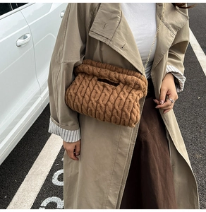 Detail of chunky knit cable pattern and golden chain on dark brown shoulder bag
