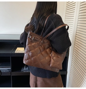 Détail d'un sac cabas matelassé marron chocolat porté par un mannequin dans un bureau
