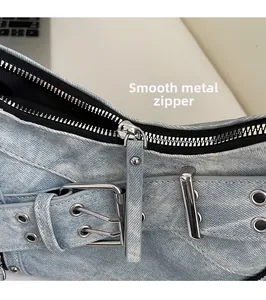 Détail du sac baguette en denim bleu clair avec fermetures éclair et boucles en métal argenté
