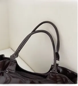 Close-up of durable top handle with silver metal buckle on brown patent leather tote bag