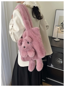 Detailed view of pink plush shoulder bag with a 3D teddy bear and wide strap on model