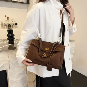 Gros plan d'un sac cabas en daim marron avec fermoir rotatif et ferrures en métal doré