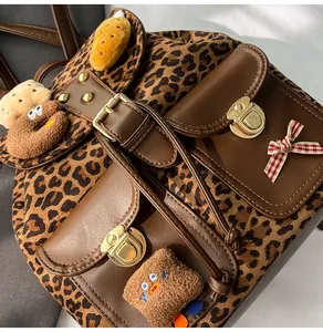 Detail of leopard print backpack with brown leather trim and plush doll charms