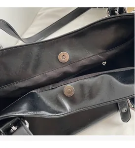 Detail view of large black tote bag featuring silver magnetic clasps and inner zip pocket