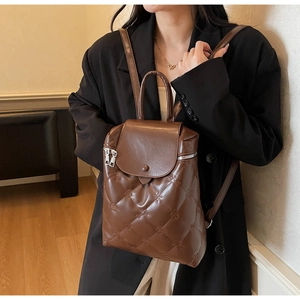 Close-up of brown quilted faux leather backpack with floral embossing and metal zippers