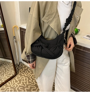 Detailed shot of a black pleated nylon cloud bag with ruched strap on a model