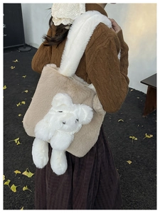 Detail of plush teddy bear tote bag with white faux fur shoulder strap in outdoor autumn setting