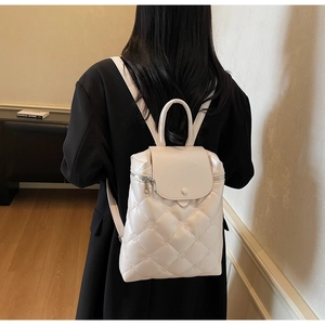 Rear view of model wearing a white quilted backpack with floral embroidery details