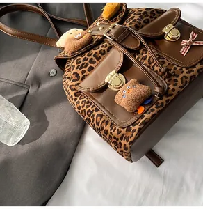 Close-up of leopard print backpack with plush charms and golden twist-lock closures