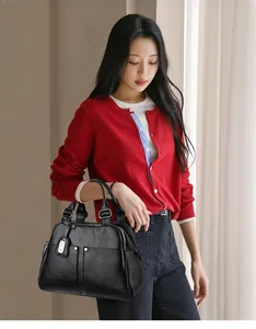 Detail view of black lychee grain leather Boston bag with silver metal charms and handle