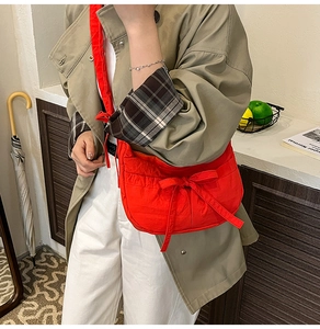 Detail shot of a bright red nylon crescent bag featuring a stylish bow knot accent
