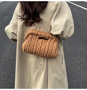 Detailed cable-knit pattern of brown shoulder bag with gold chain on trench coat