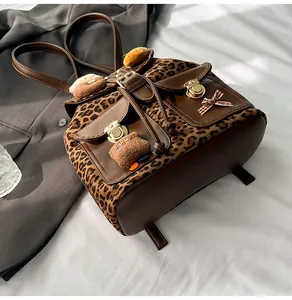 Detailed leopard print backpack featuring dual front pockets and a cute plush bear charm