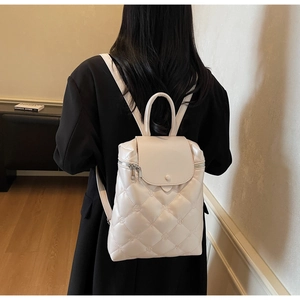Rear view of a model wearing the cream quilted faux leather backpack with metallic zippers