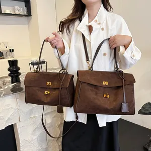 Détail de sacs fourre-tout marron mat avec fermoirs dorés et texture aspect suède