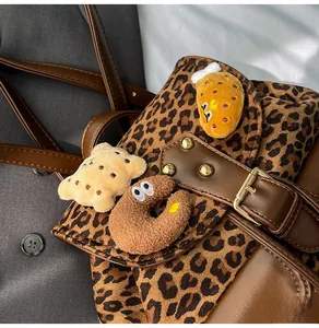 Detail of leopard print backpack with plush cartoon charms and brown leather flap